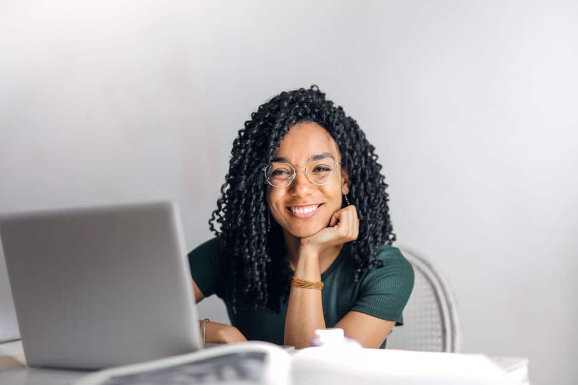 CAMS exam guide - Confident businesswoman working on laptop representing career advancement and higher earning potential through CAMS certification